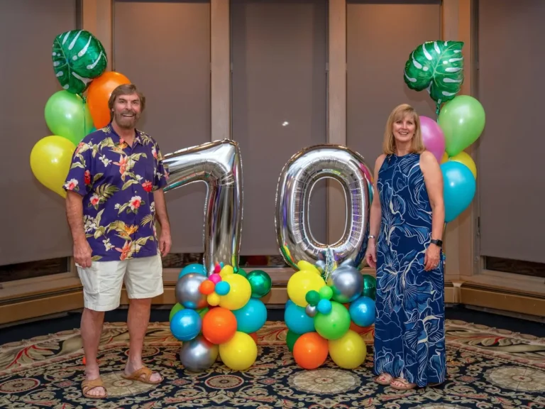 70th-bday-party-event-photos-uav-vision-media-minnesota-dec-birthday-couple-standing-with-balloon-arch-Chris-Blaeser-UAV-Vision-Media